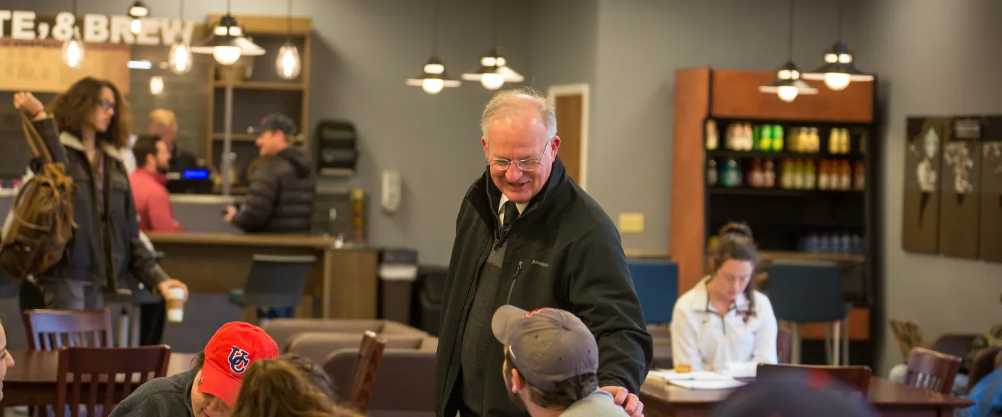 An older man speaking to a young adult