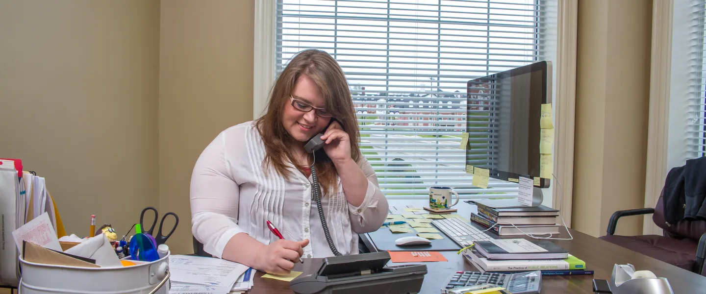 A student working at a desk answering a phone