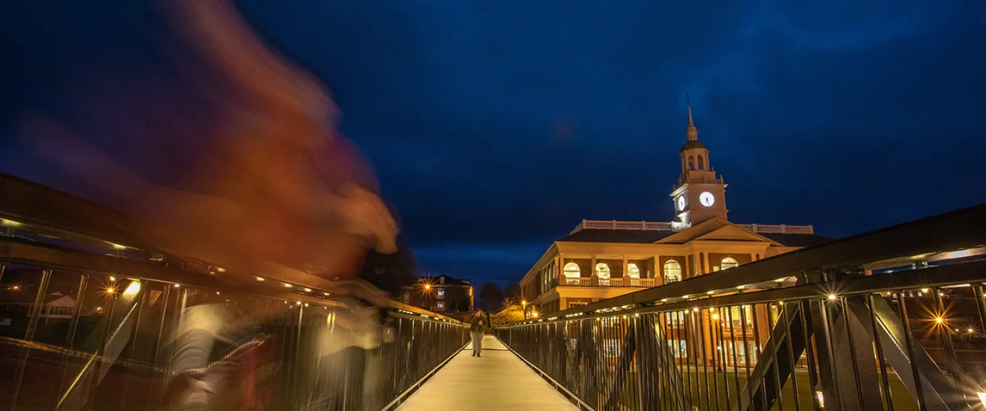 A student walks across the viaduct at night. 
