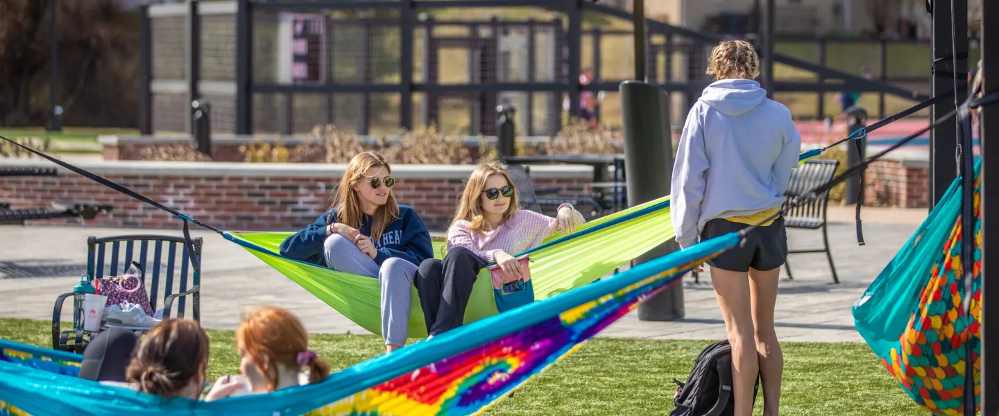 Students sitting on hammocks in a courtyard