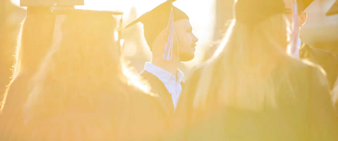 Students wearing cap and gown at sunset