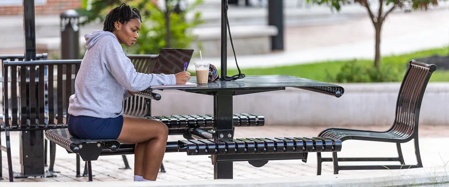 A student sits outside in the quad doing coursework 