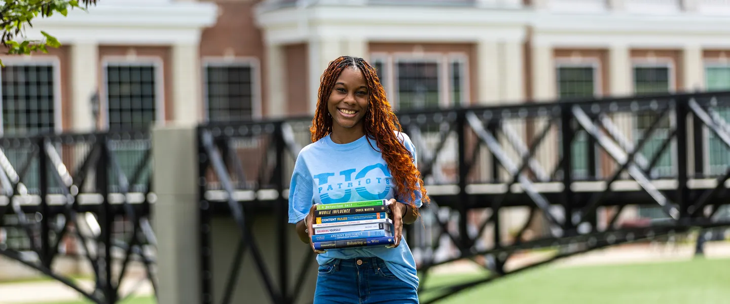 A student holds textbooks outside on Cumberlands campus. 