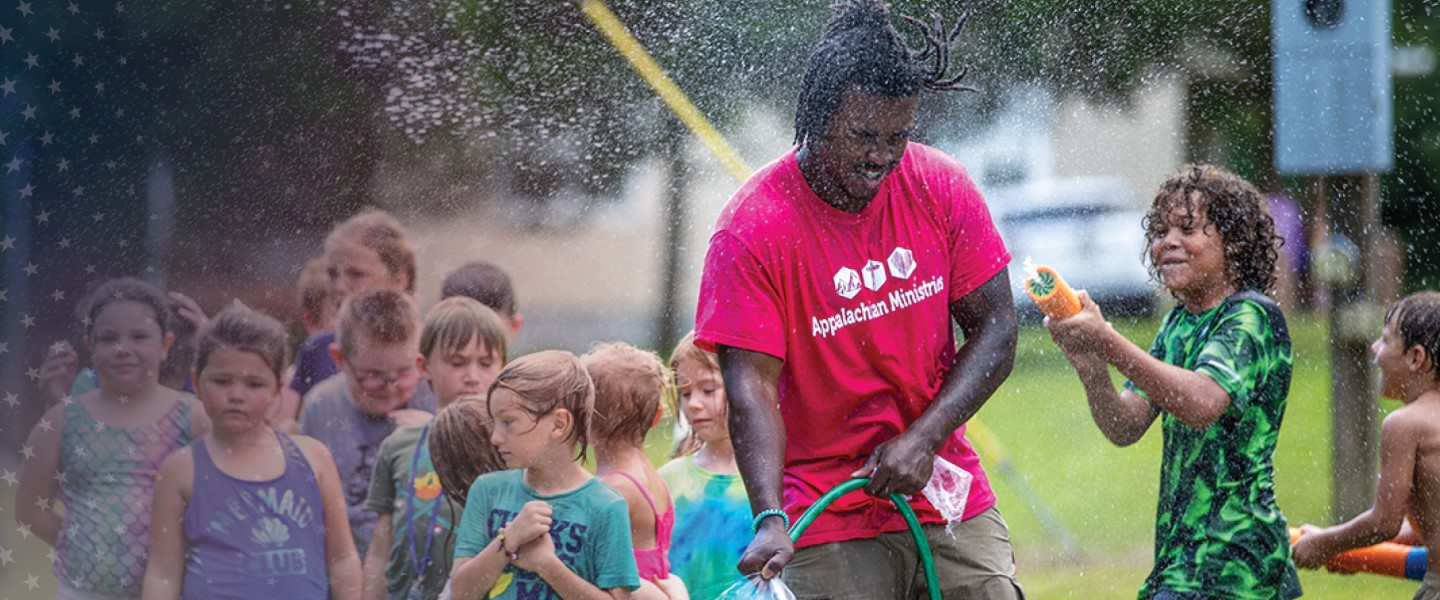 A Cumberlands students plays in a water hose with local children during a summer event. 