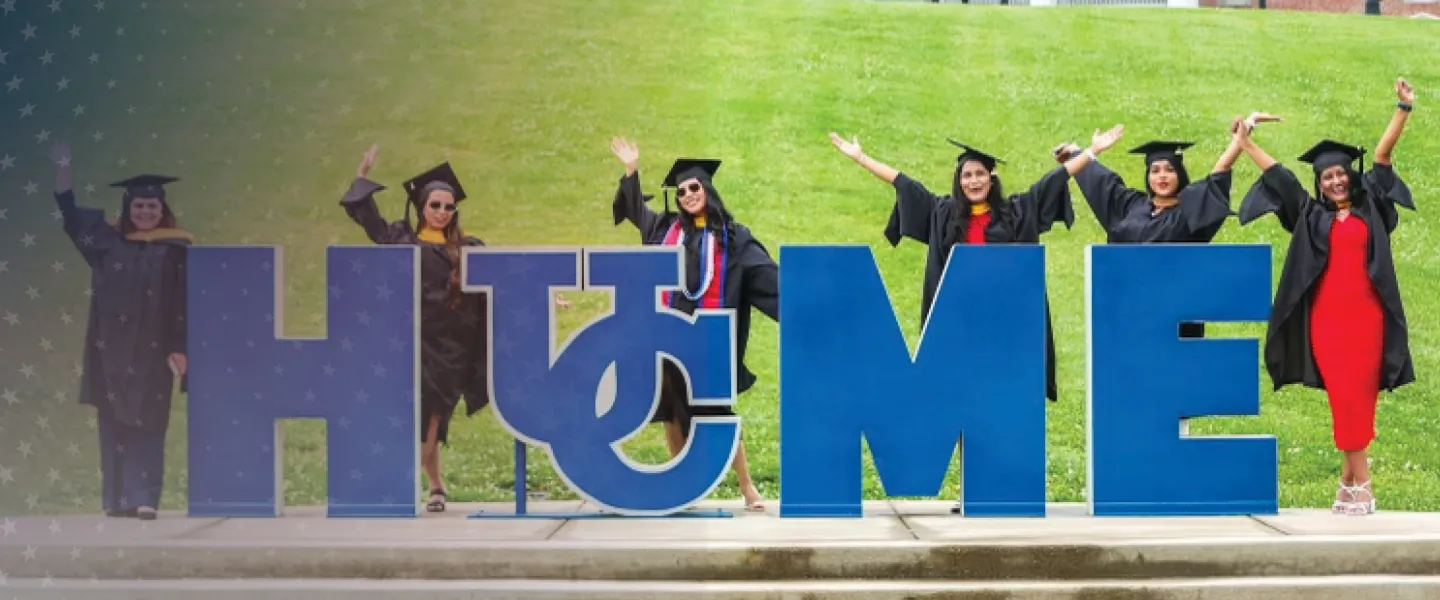 Students celebrate at the Cumberlands HOME sign during graduation. 