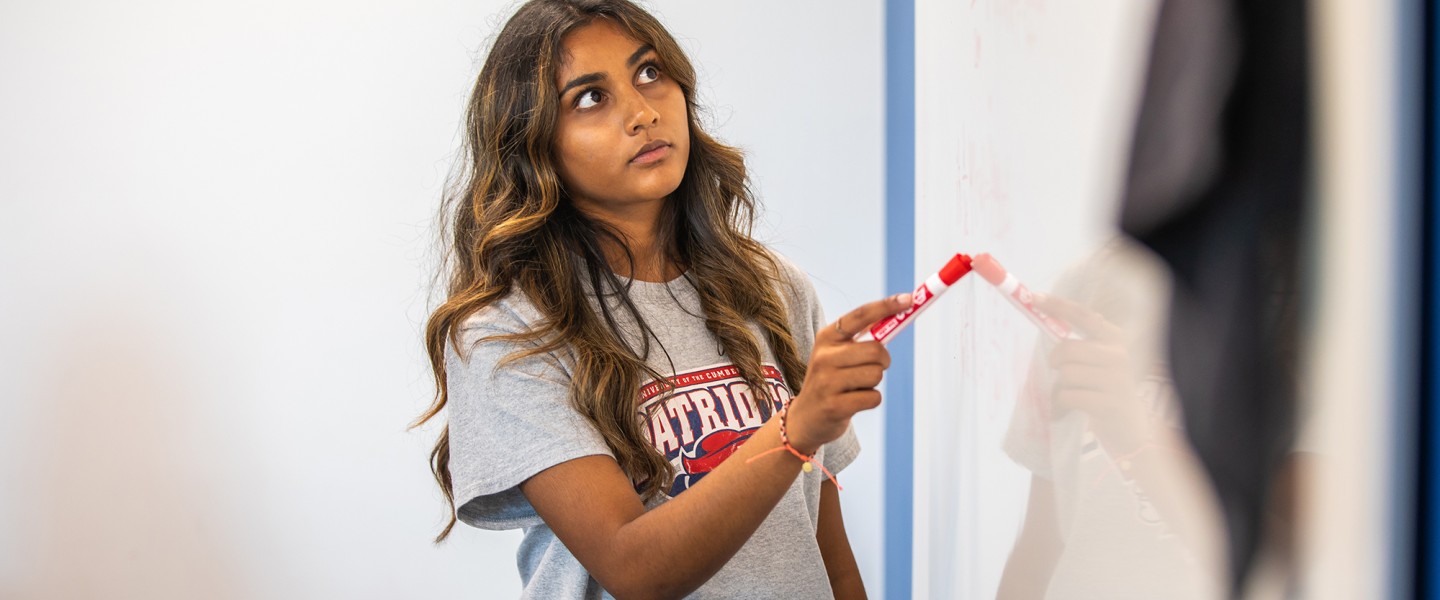 A student spends some time prepping for an assignment while using a whiteboard.