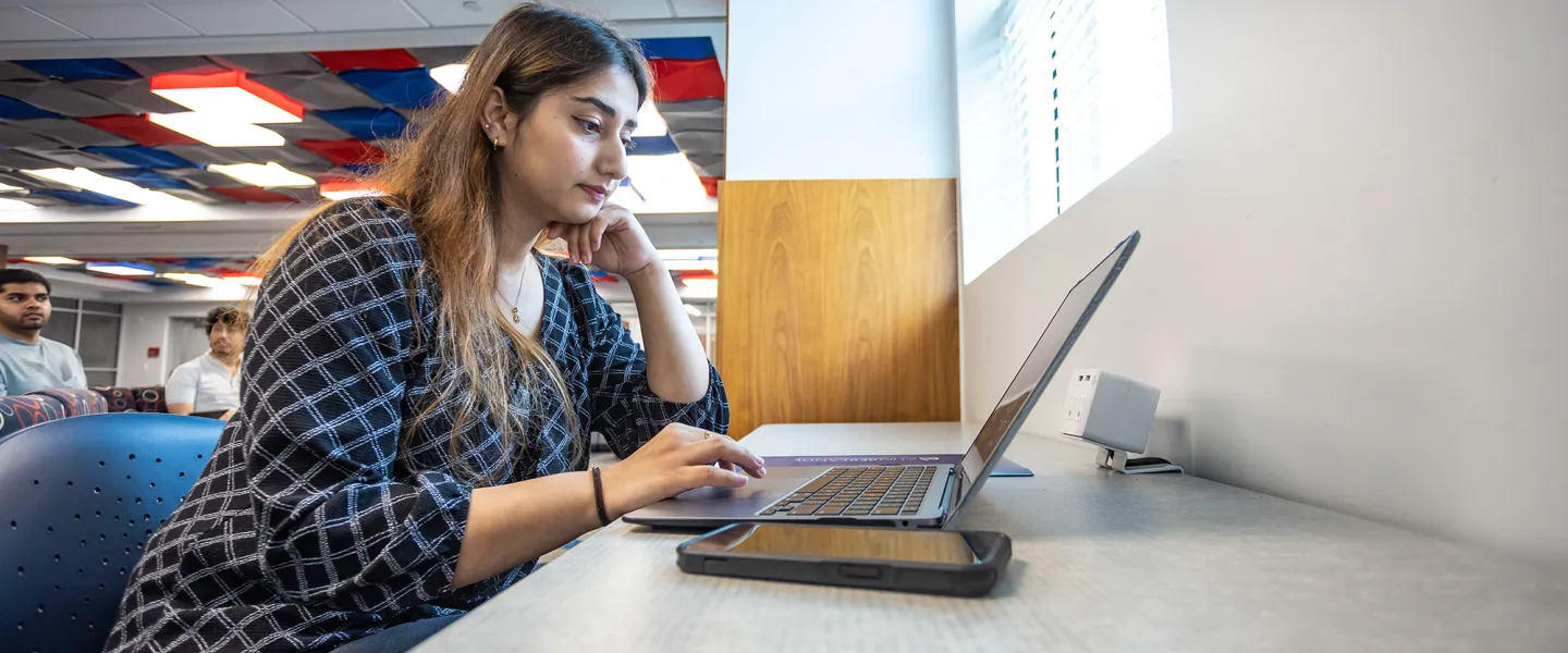 A graduate business student studies in the library. 