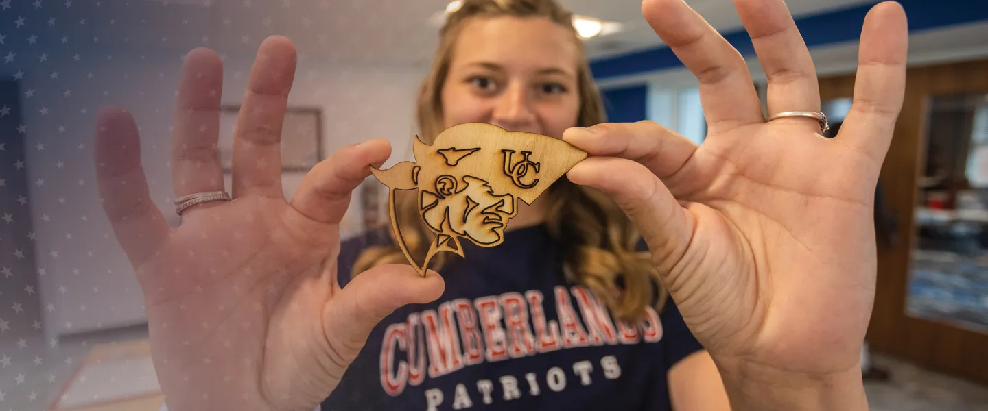 A student displays a woodcraft she made in the library maker space. 