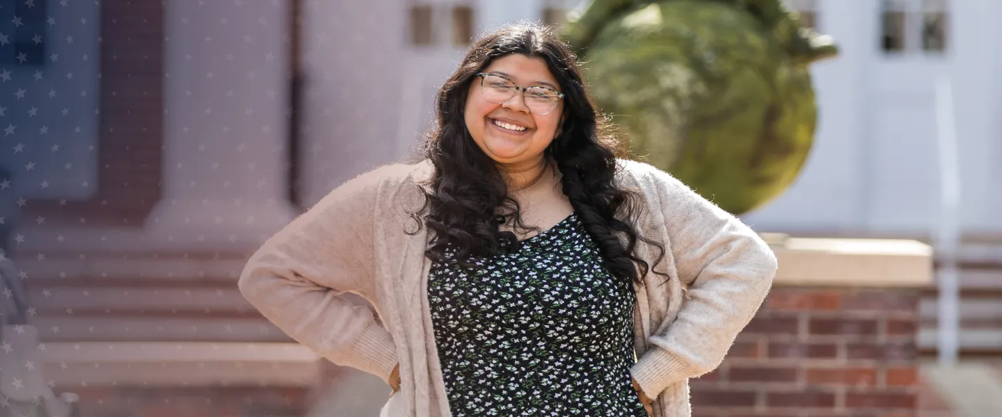 A student poses after class in front of the education building. 