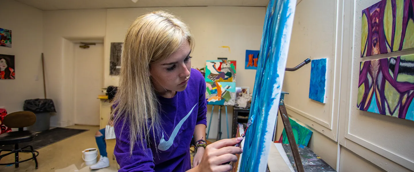 An art student works on a painting in the studio. 