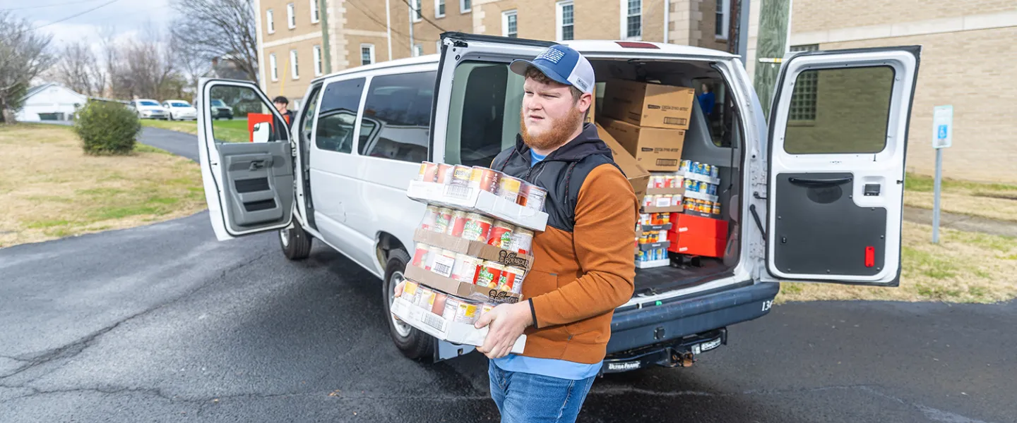 A student carries donated food into a food pantry. 