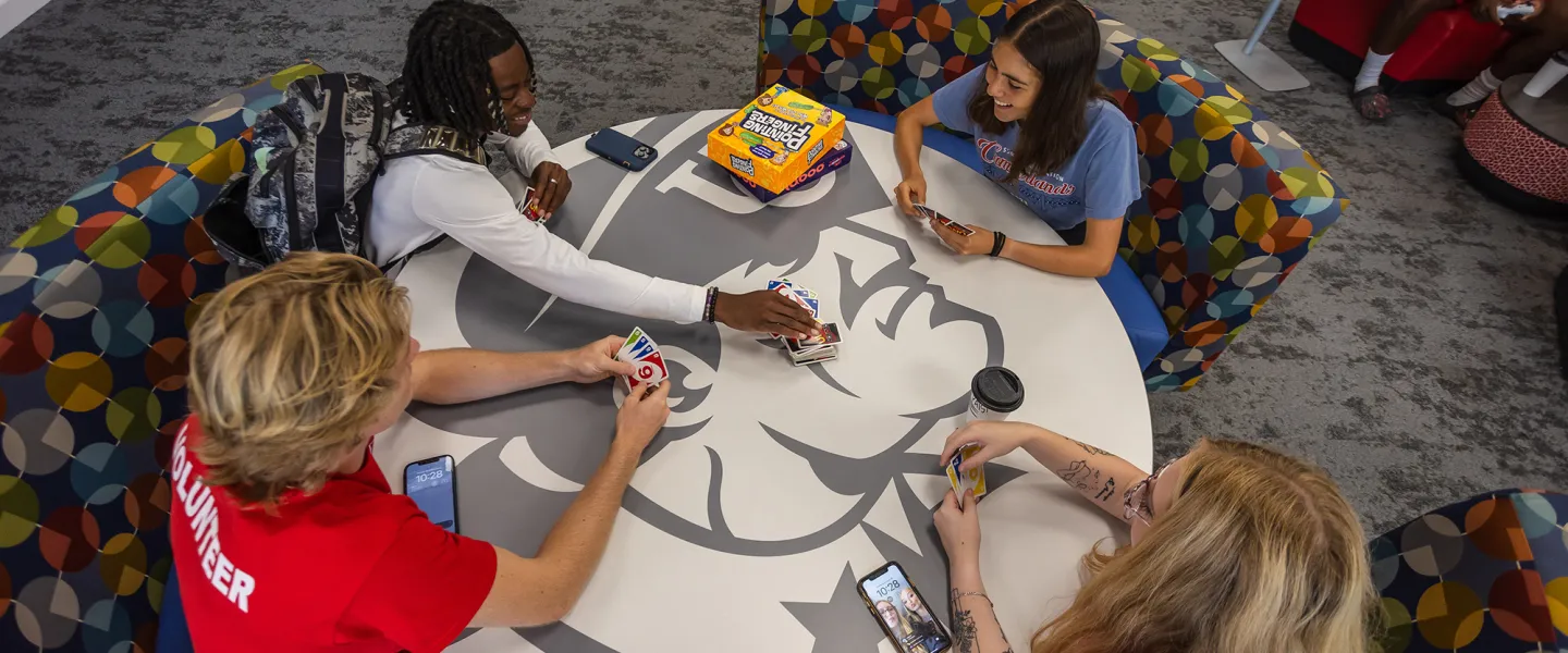 Students play cards around a table in the student center.