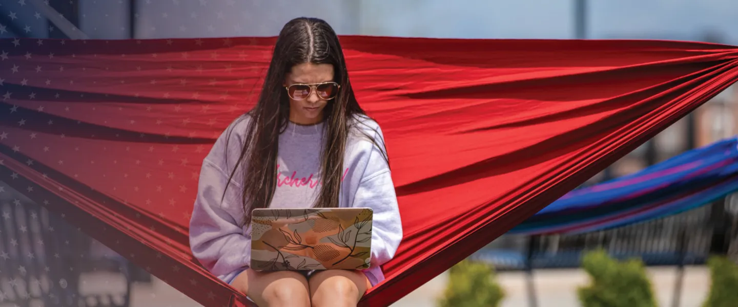 A student works on a computer from her hammock.