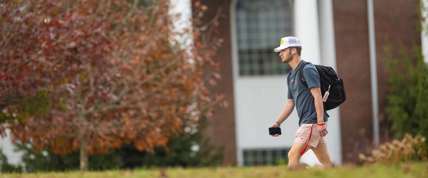 A student walks to class with his backpack. 