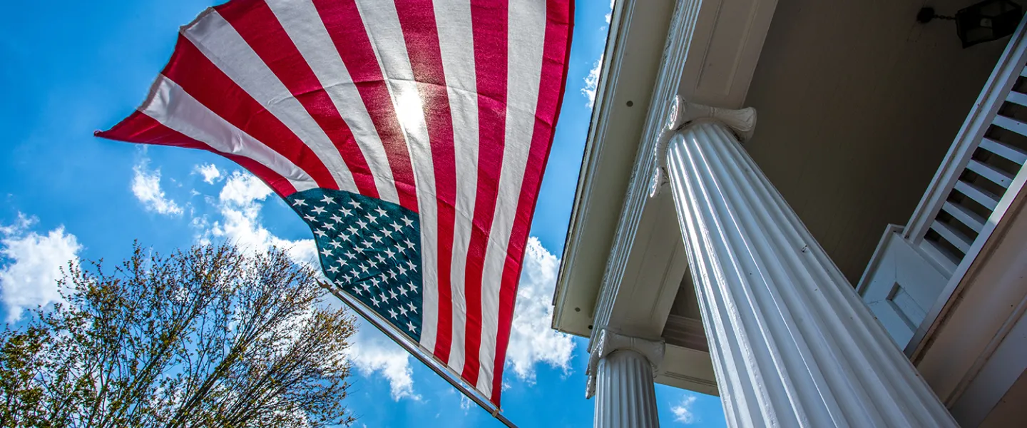 An American flag is displayed on a building on campus. 