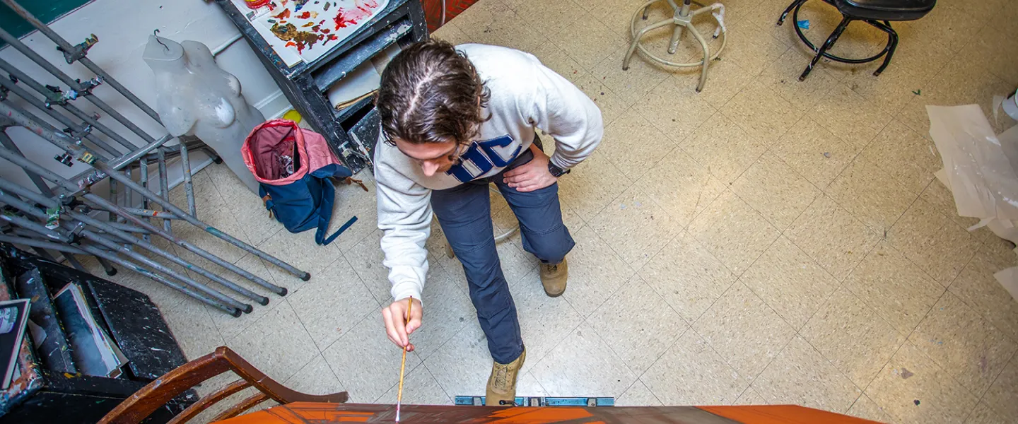 A male art student works on an abstract canvas. 