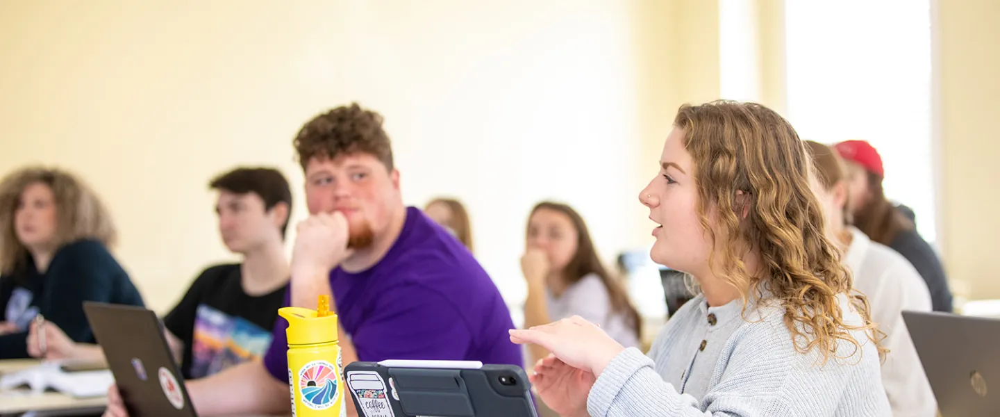 A female student discusses a topic in class. 