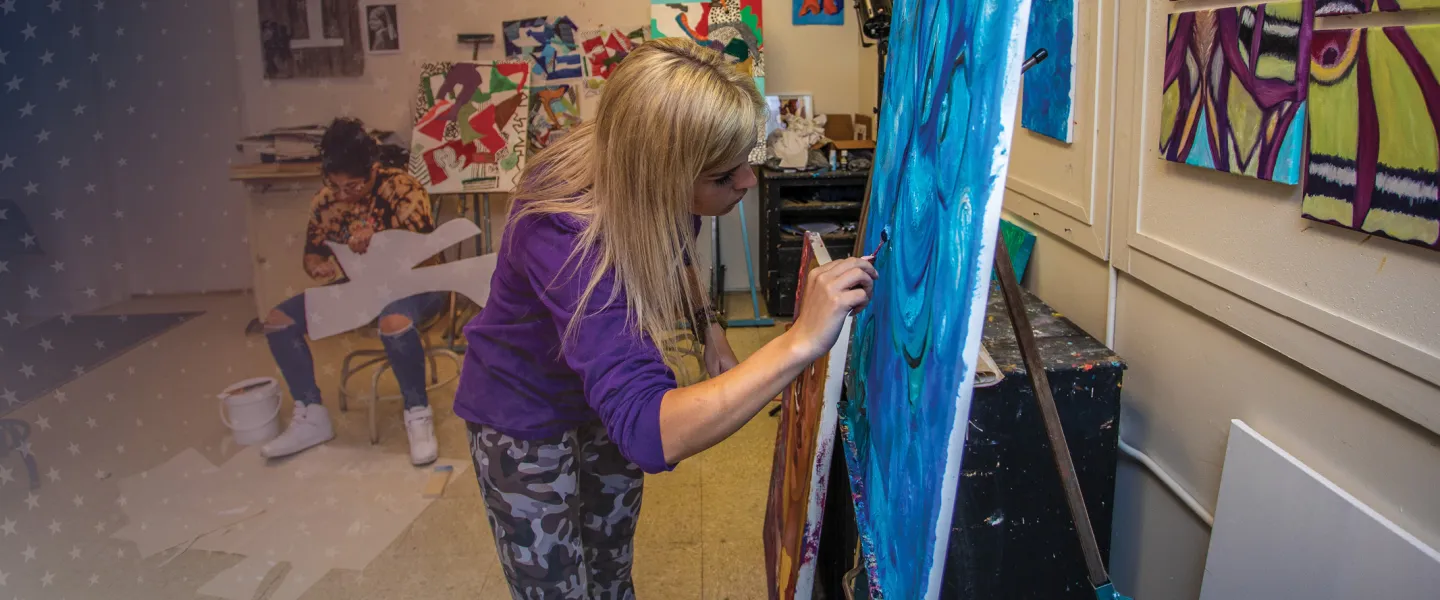 A female art student paints on her canvas. 