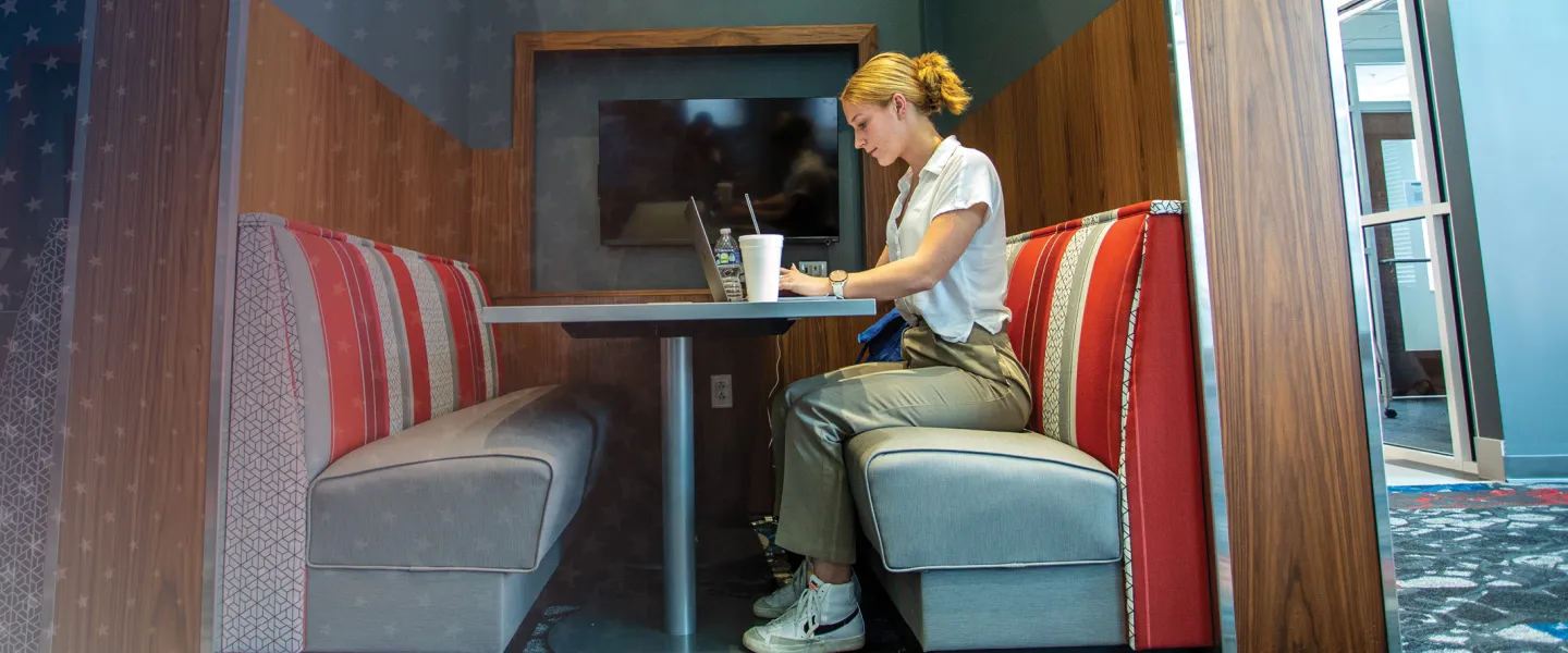 A female college student studies alone at a booth in the library.