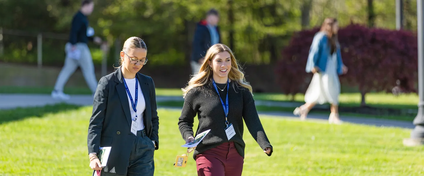 Two female business students walk across campus during the annual business forum. 