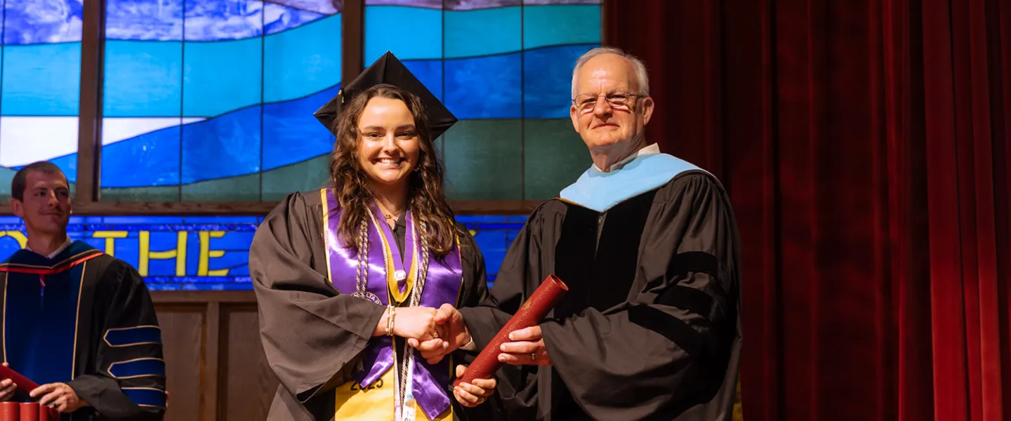 A female honors student accepts her diploma from President Cockrum. 