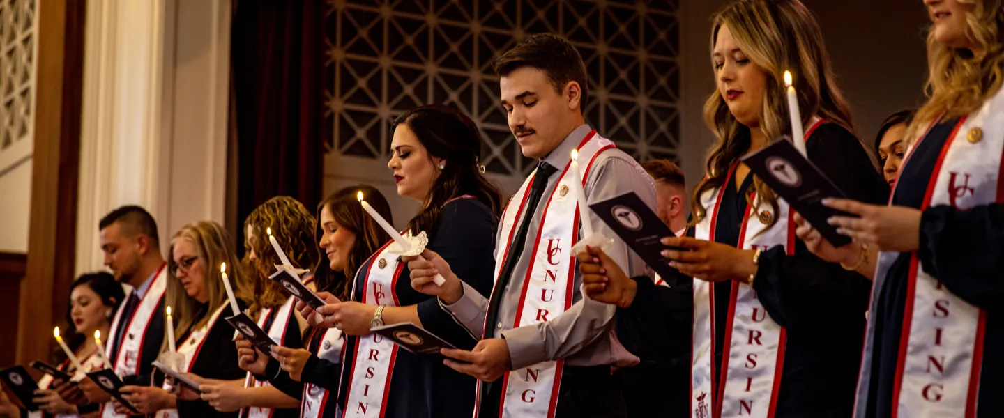 Nursing graduates hold candle and read their oath during a ceremony. 