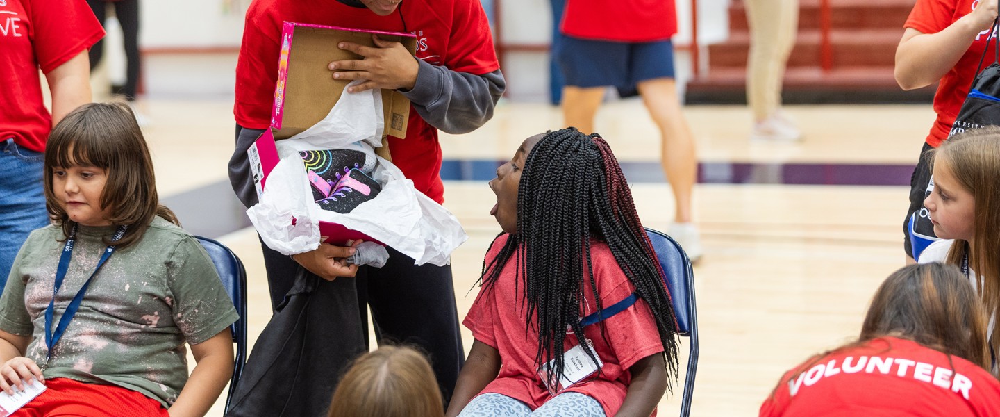 A female college volunteer shows a local female elementary student a new pair of shoes during Cumberlands annual service event. 