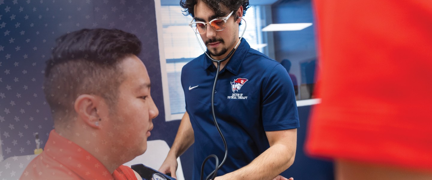 Two male DPT students check blood pressure during a clinical lab. 