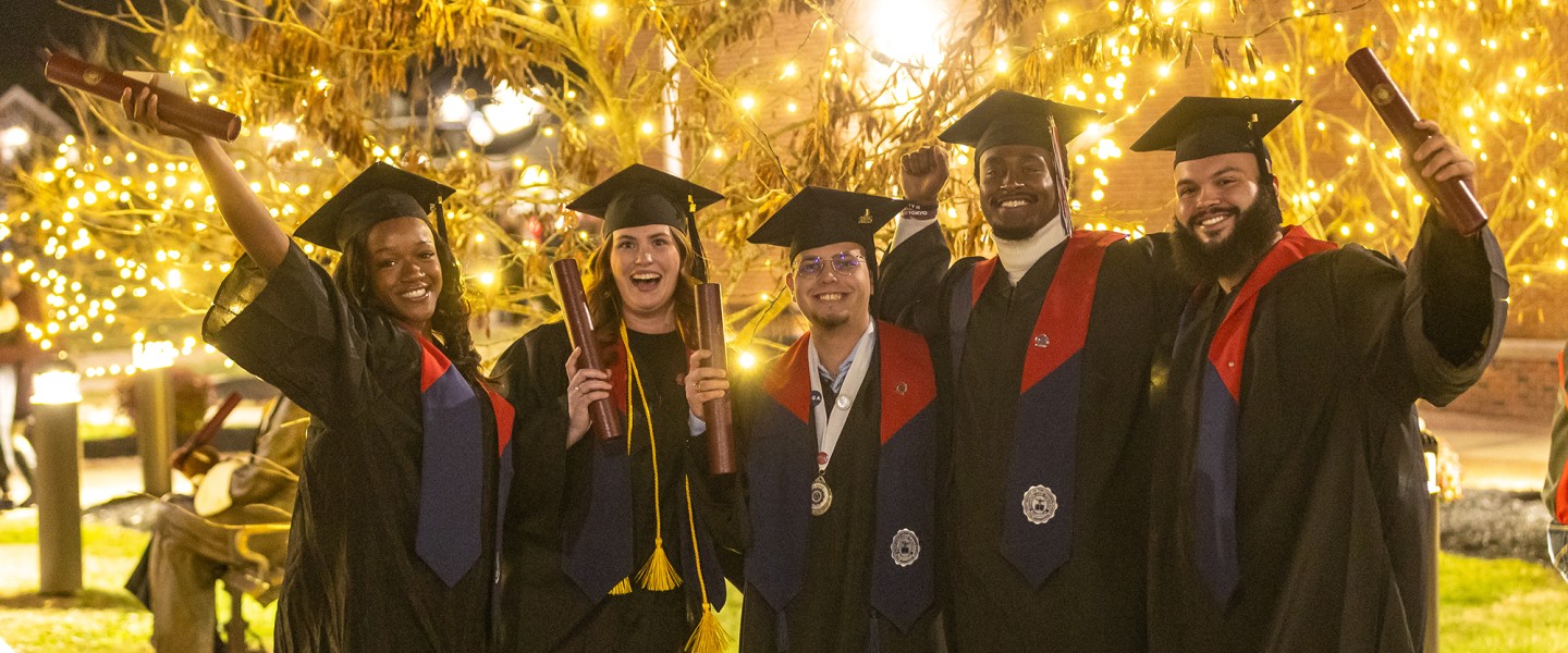 Five students pose in their caps and gowns while holding their diplomas following Cumberlands December graduation ceremony. 