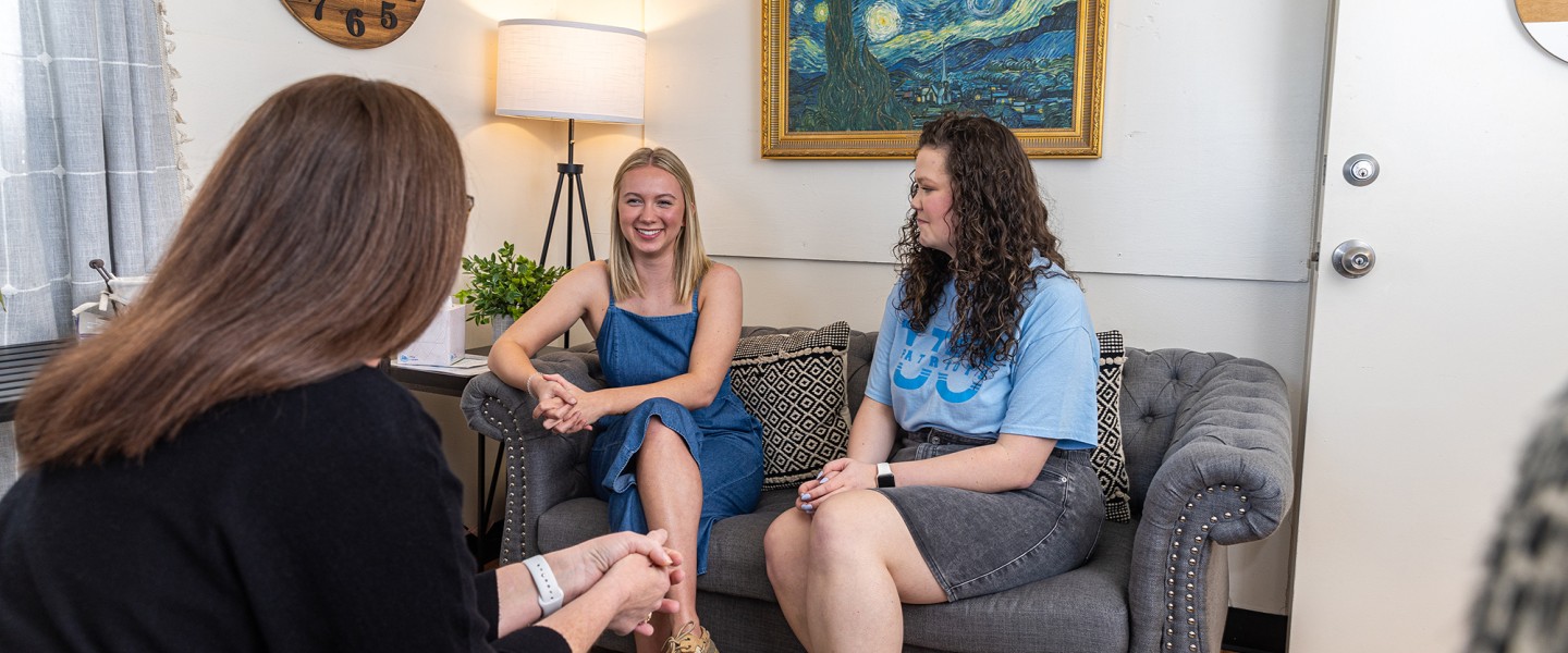 Two female college students visit with an advisor in the campus counseling center. 
