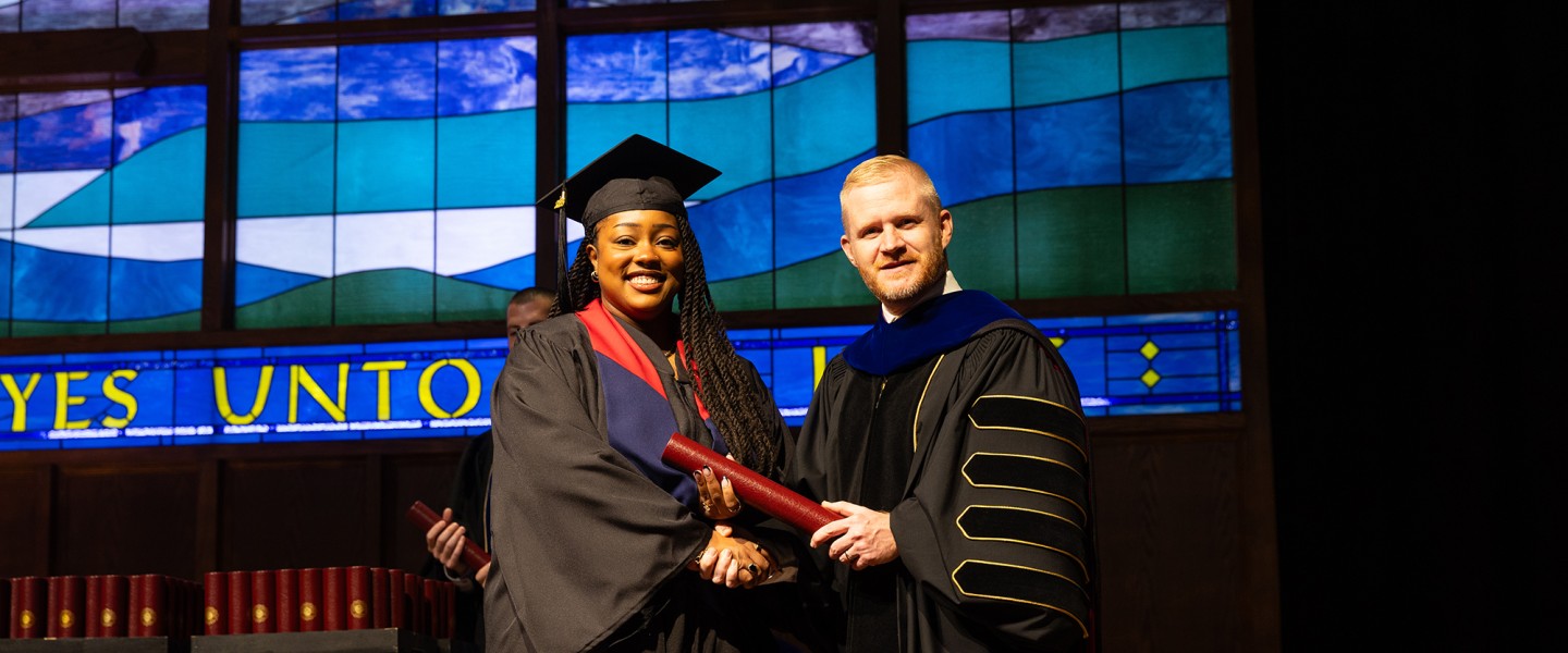 A female graduate accepts her diploma from President Young. 