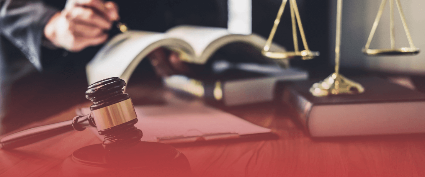 Judge Writing in Book with Gavel and Scales in Foreground