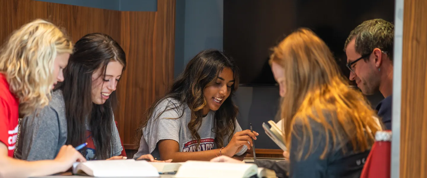 A group of students study together at a table in the library. 