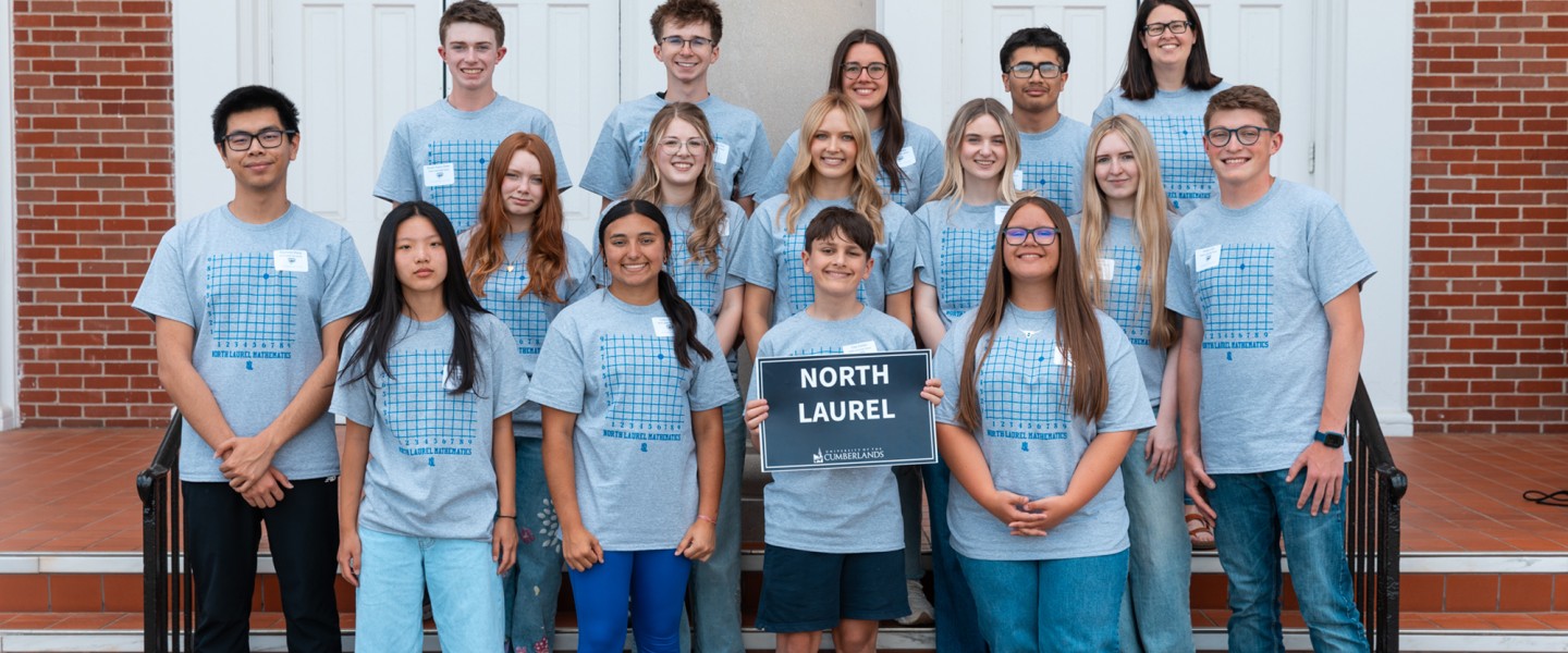 A group of high school students hold a sign with the school name on it at the annual math contest. 