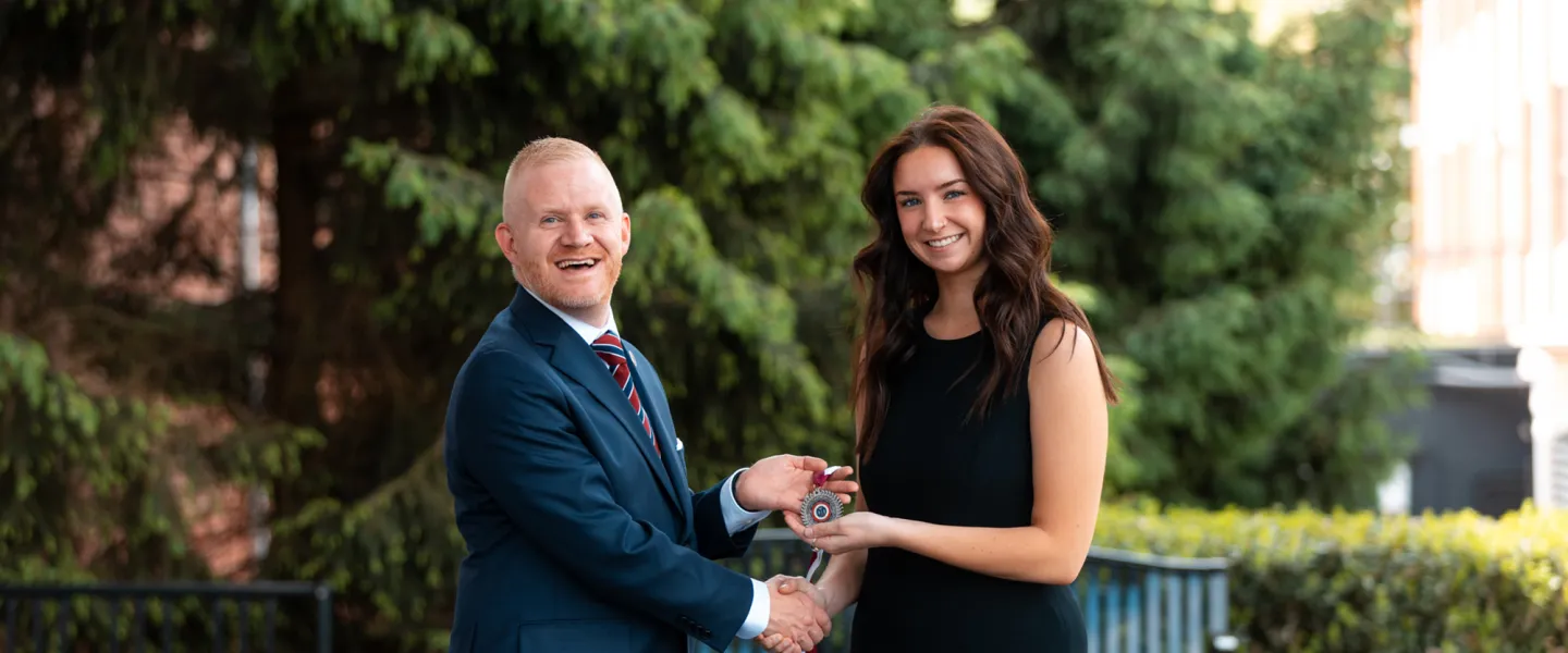 President Quentin Young presents an award to the 2026 presidential scholar.
