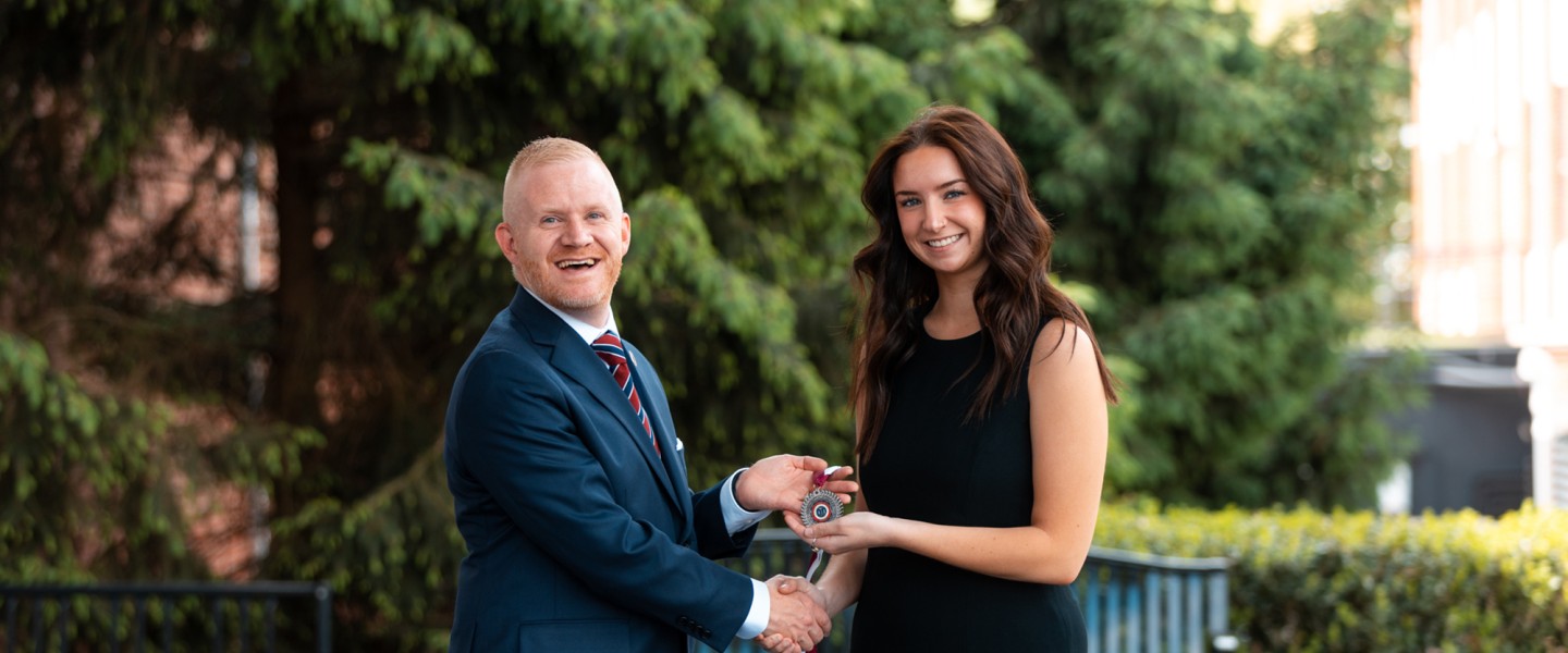 President Quentin Young presents an award to the 2026 presidential scholar.