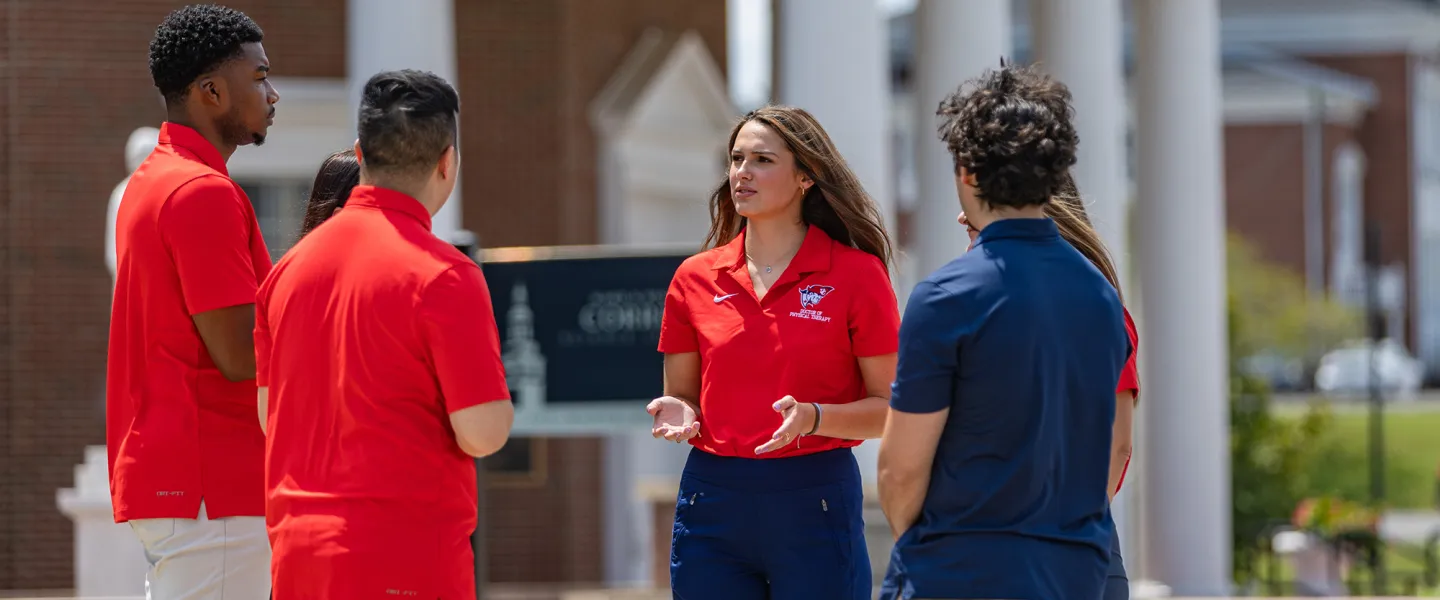 A female physical therapy student leads a discussion among a group of students. 