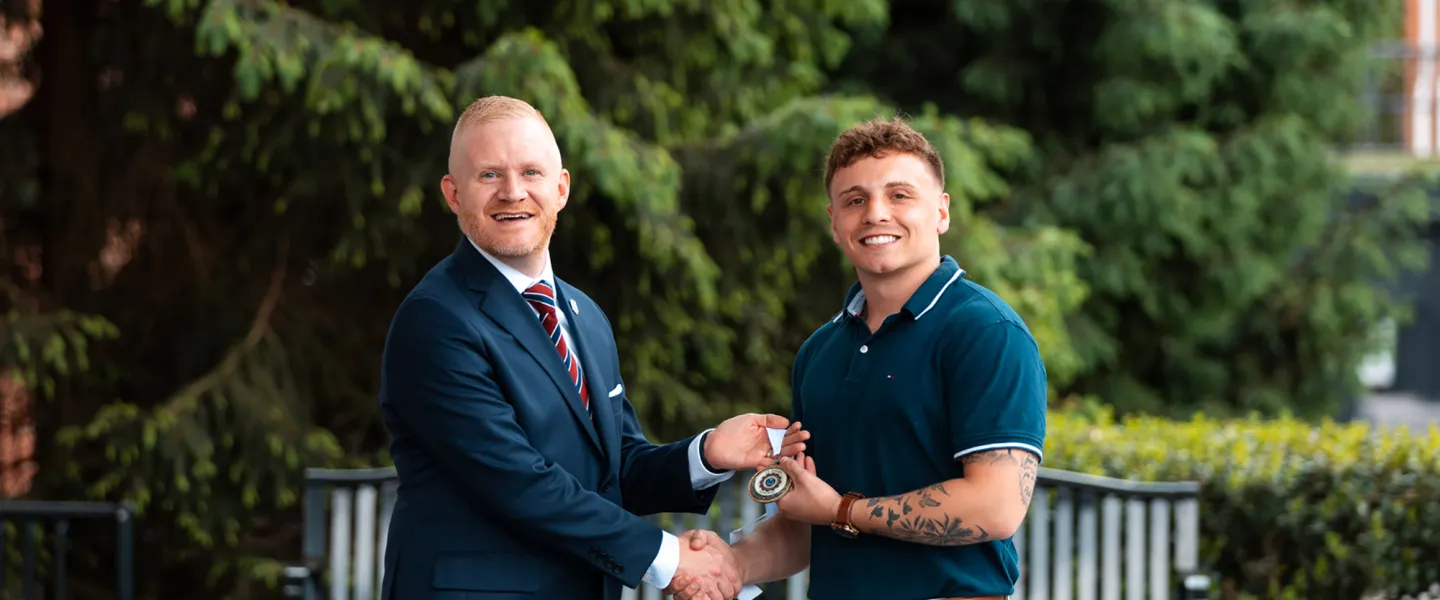President Young presents an academic award to graduate Jacob Canada.