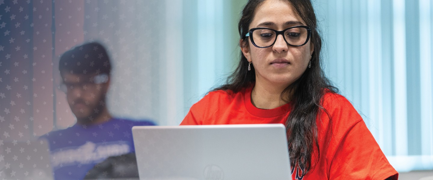 A female students engages in research while on her computer in class. 
