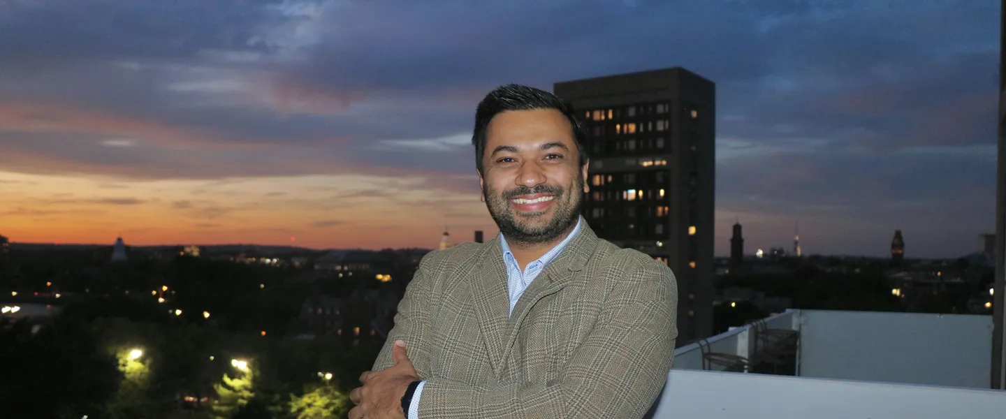 Dr. Aashis Luitel poses for a photo with a cityscape behind him. 