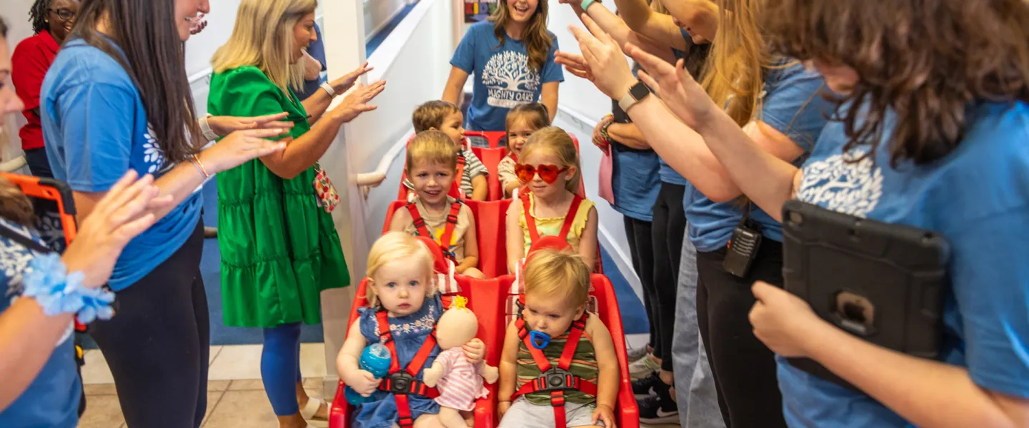 Workers at the Mighty Oaks Early Learning Center push children in a stroller. 