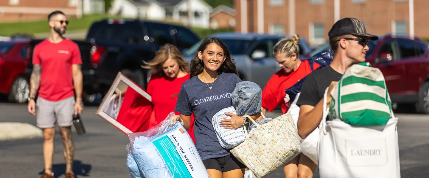 A freshmen female carries pillows from the parking lot to her dorm during move-in weekend. 