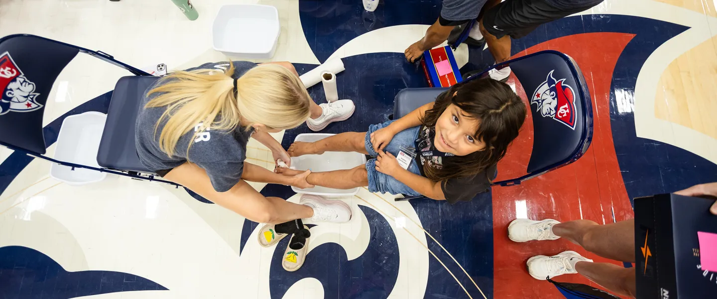 A college volunteer washes the feet of a local student prior to giving her a new pair of shoes during the annual Shoes 4 the Soul event. 
