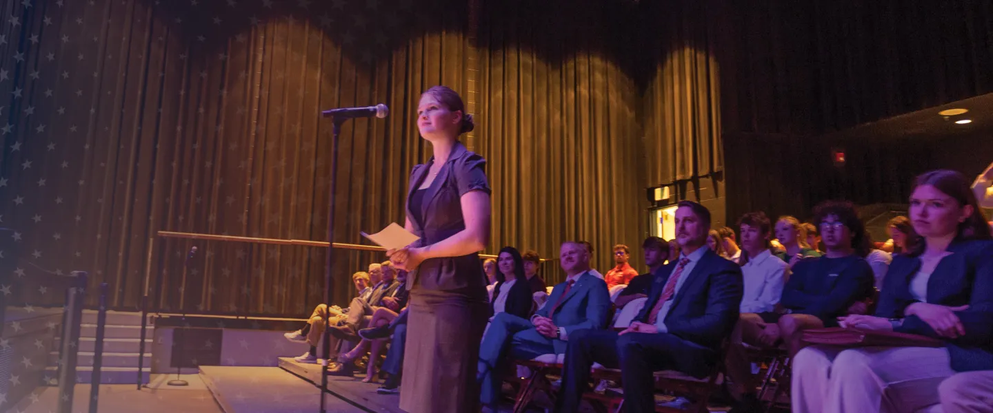 A female law student stands at a microphone and asks a question of Supreme Court members during a campus event. 