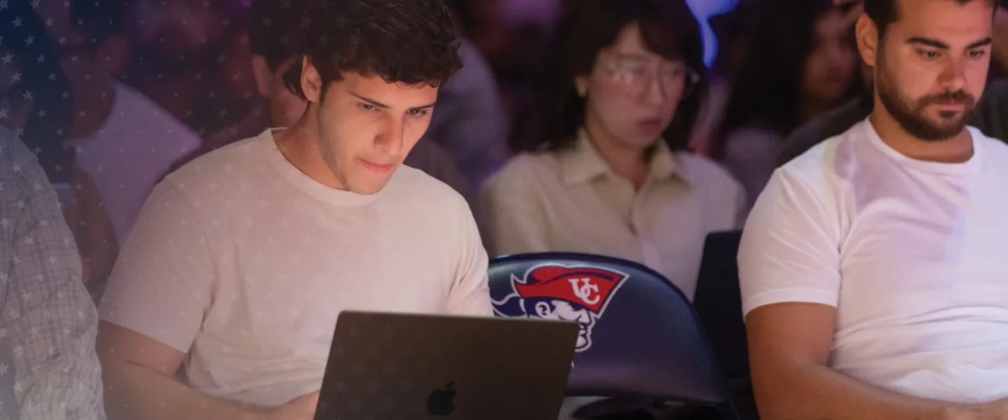 A group of students shown sitting in a seminar with their laptops out. 