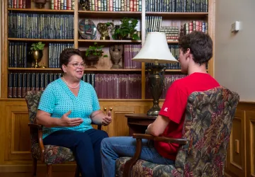 A faculty member sitting across from a student having a conversation
