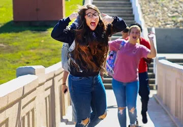 A student jumping for a picture while on a boardwalk