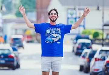 Student posing for a picture with both arms up