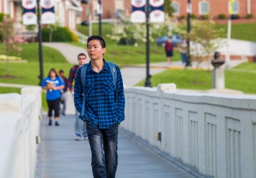 A student walking across a bridge