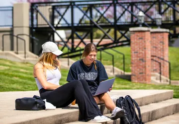Two students seated on steps outside